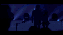 a group of people are standing on a stage with blue lights
