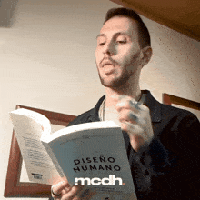 a man reading a book called diseno humano