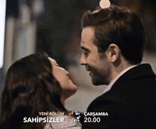 a man and a woman are kissing in front of a sign that says sahipsizler