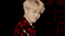 a man in a red and black plaid jacket is making a peace sign .