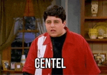 a man in a red and white shirt is standing in a living room with the word centel on his chest .