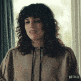 a woman with curly hair is wearing a hoodie that says netflix on the front