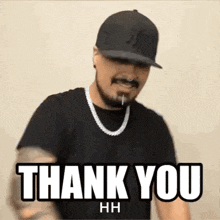 a man wearing a hat and a necklace is giving a thank you sign .