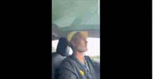 a man wearing a yellow hat and a black shirt is driving a car .