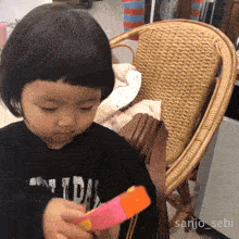 a little girl sitting in a chair with the name sanjo_sebi on the bottom
