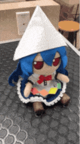 a stuffed doll with blue hair and red eyes is wearing a white hat