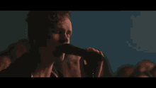 a man is singing into a microphone in front of a crowd