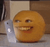 an orange with a smiley face is sitting on a table next to a phone .