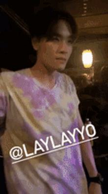 a man wearing a tie dye shirt with the name laylayyo on it .