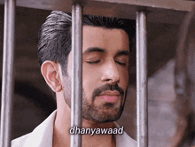 a man with a beard is behind bars with the word dhanyawaad written below him