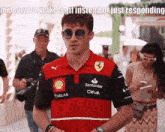 a man wearing sunglasses and a red shirt with santander ceva written on it