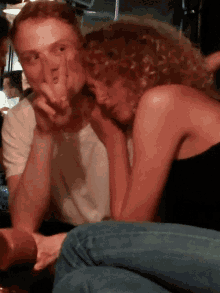 a man and a woman are sitting next to each other and the woman is covering her face