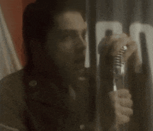 a man is holding a microphone in front of a glass door .