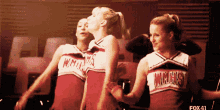 three cheerleaders wearing red uniforms with wmhs on them