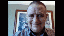 a man smiles in front of a framed picture