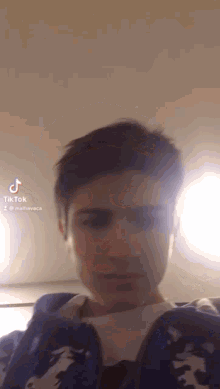 a young man wearing a blue jacket is taking a selfie with his phone .