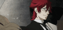 a man with red hair wearing glasses and a black suit