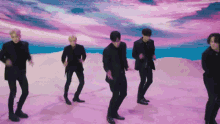 a group of men in black suits are dancing in a desert .