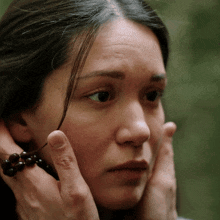 a close up of a woman 's face with a person holding her face