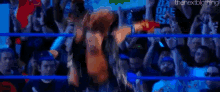 a wrestler is standing in the middle of a wrestling ring with his arms outstretched .