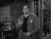 a black and white photo of a man wearing a vest and jacket