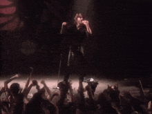 a man singing into a microphone in front of a crowd at a concert