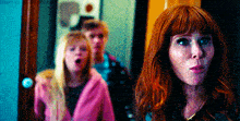 a woman with red hair is standing in front of a group of people with the words haynan on the bottom right