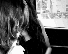 a woman with long hair is sitting in a car looking out the window .