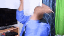a man in a blue shirt is dancing in front of a flat screen tv