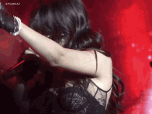 a woman in a black lace dress is singing into a microphone with gifcamlas written on the bottom