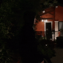a red house is lit up at night with a fence around it