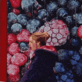 a woman in a purple coat is walking in front of a picture of berries