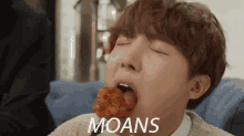 a young man is eating a piece of chicken with his eyes closed and the word moans written next to him .