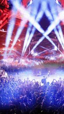 a crowd of people at a concert with blue and red lights coming out of the ceiling
