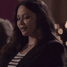a woman wearing a black jacket and a striped shirt is smiling