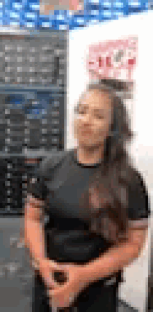 a woman in a black shirt is standing in front of a shelf of shoes .