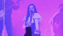 a woman sings into a microphone while a man plays a guitar
