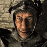 a man is wearing a helmet and armor and looking at the camera .
