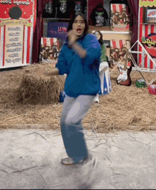 a woman in a blue sweatshirt is dancing in front of a sign that says lions