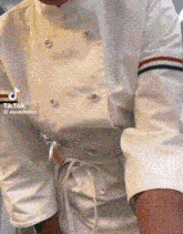 a close up of a person wearing a white chef 's jacket and shorts .