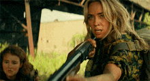 a woman is holding a shotgun in a movie scene .
