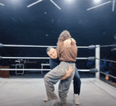 a wrestler is carrying another wrestler on his back in a ring