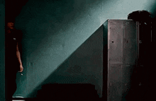 a person is standing in a dark room with lockers and a light shining through the lockers