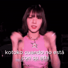 a girl in a pink tank top is making a fist gesture and says kotoko cuando no esta con su athi .