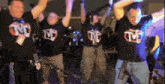 a group of people wearing tnt shirts are dancing together