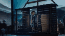 a woman in a cowboy hat is standing in front of a wooden cabin