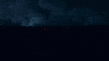 a group of people are standing in the dark watching a storm