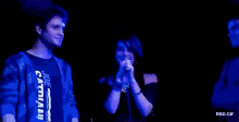 a woman singing into a microphone while a man looks on