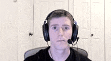 a man is wearing headphones and a microphone while sitting in a chair .