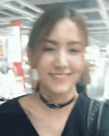 a woman wearing a choker and a black shirt is smiling